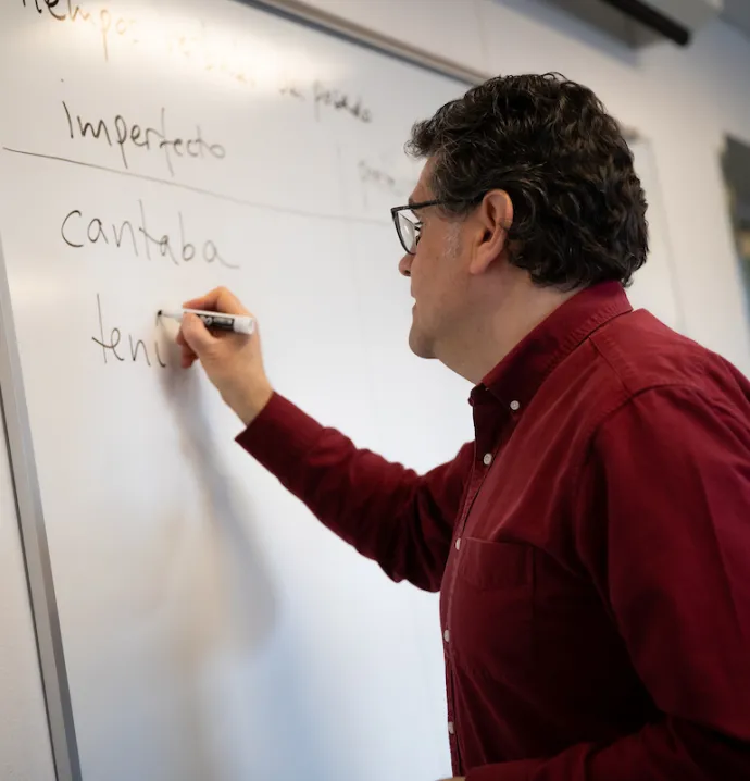 Juan Carlos Castillo writing in Spanish on a white board
