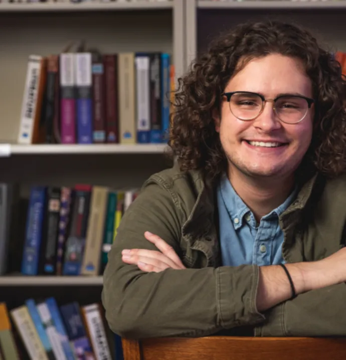 Student sitting in front of full bookcase