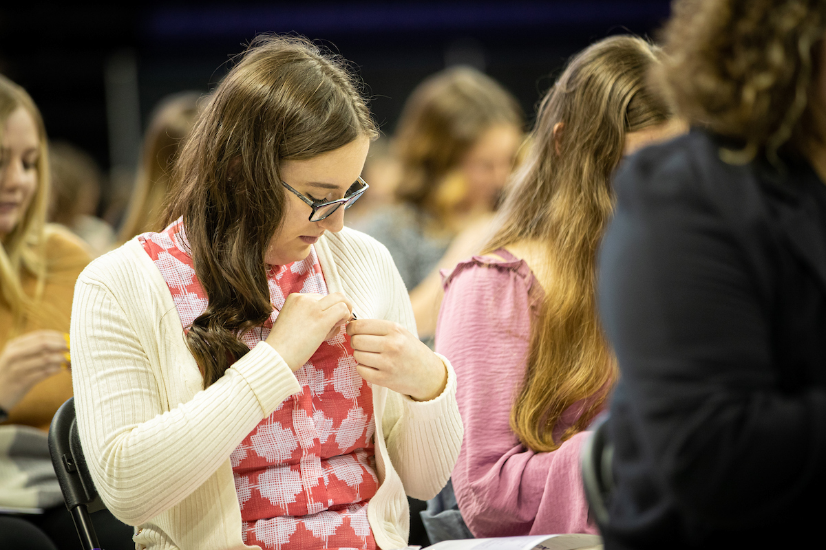 Student pinning pin on herself at Convocation