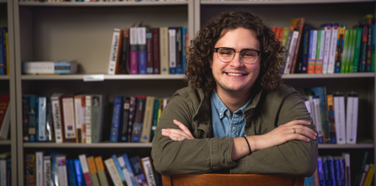 Student sitting in front of full bookcase