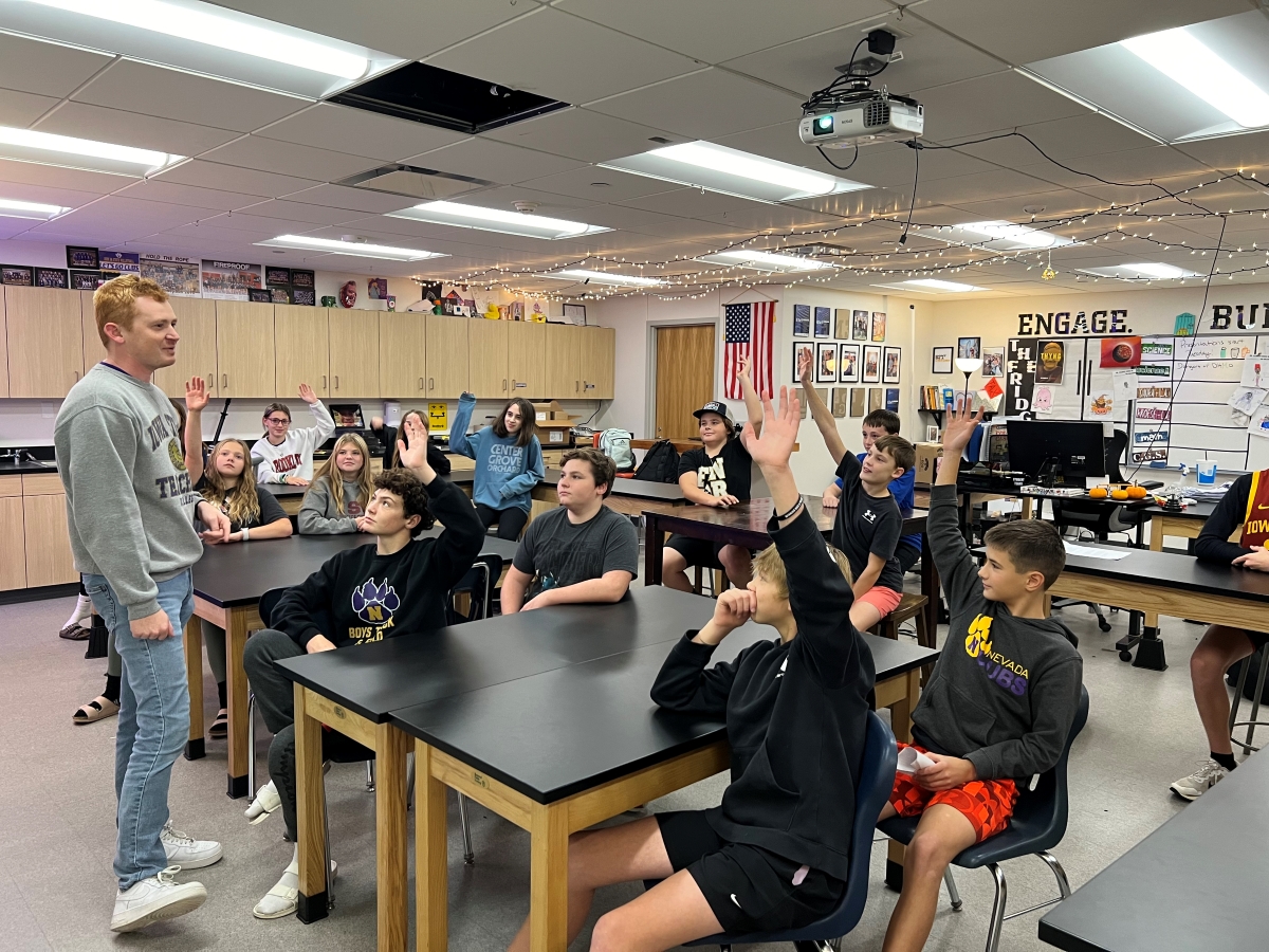 Zach Lillquist in classroom with students raising their hands
